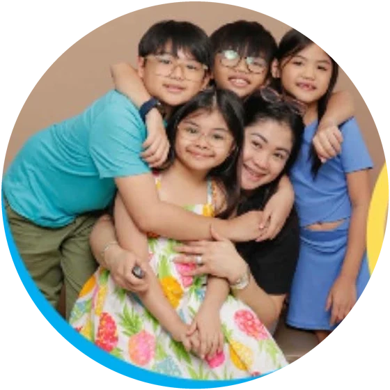 A group of smiling children hugging their teacher